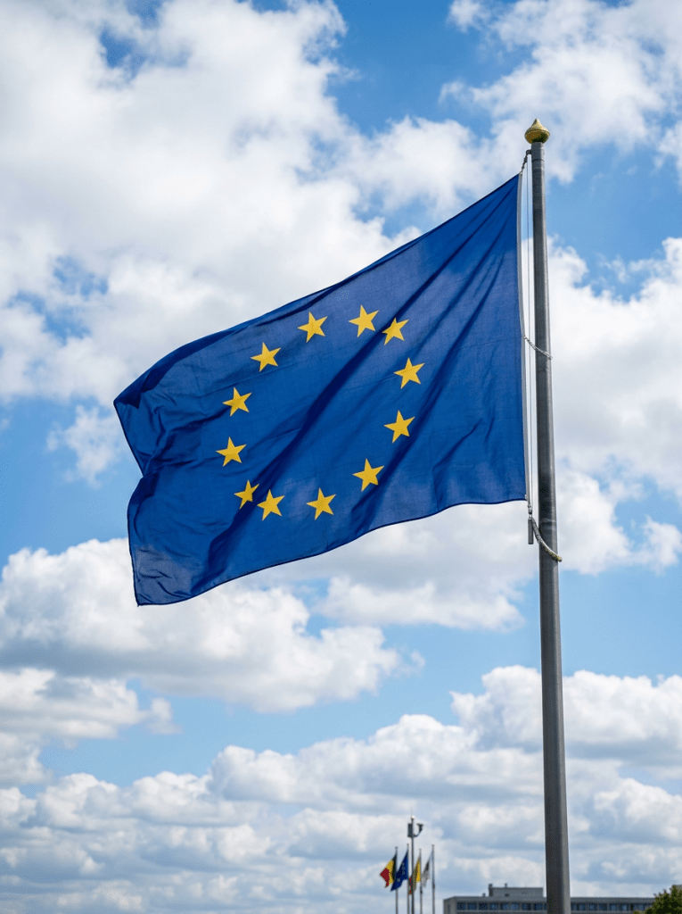 European Union flag with twelve yellow stars in a circle on blue background flying on a flagpole